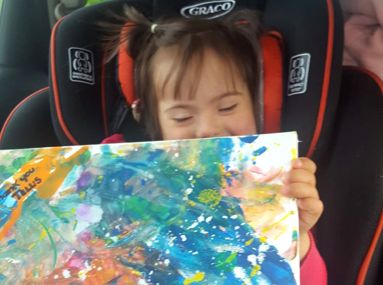 Amelie sitting in the car showing her painting for Telus