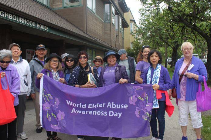 Photo of seniors outside our House holding up a bright purple World Elder Abuse Awareness Day banner in 2018